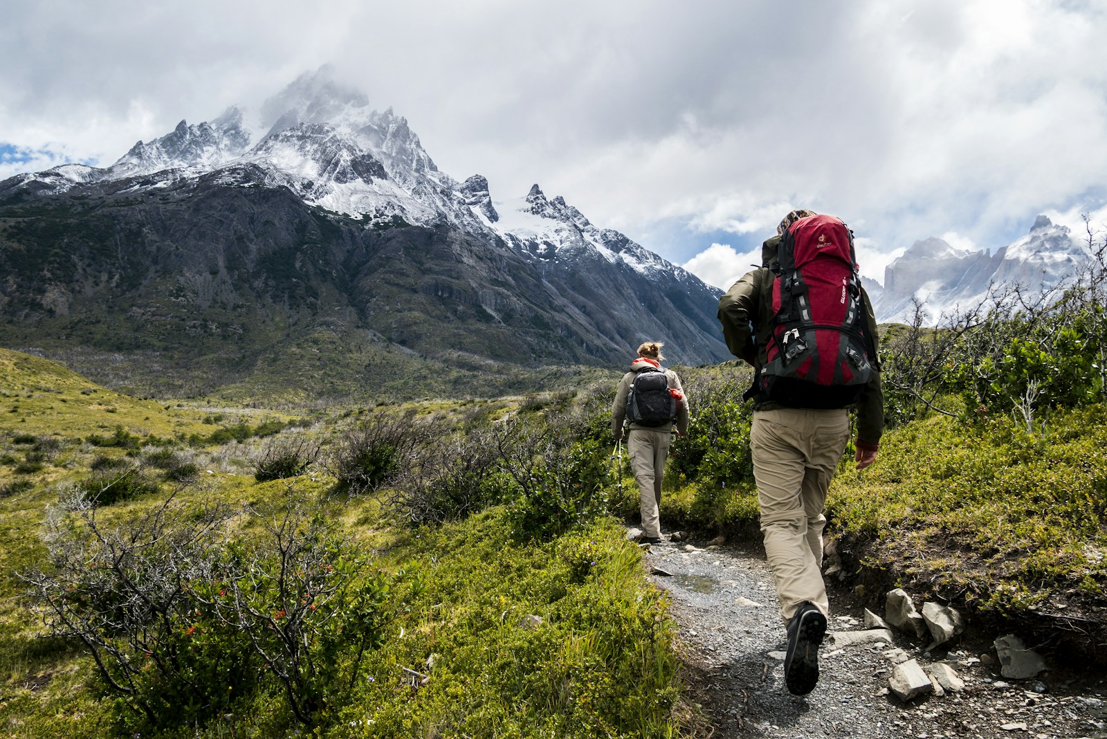 Two people hiking toward mountain peaks — the journey forward